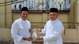 Calon Wakil Gubernur Aceh Fadlullah menerima hadiah buku dari anak keuchik Leumiek, di halaman Mesjid Keuchik Leumiek, Banda Aceh, Jumat (11/10/2024).