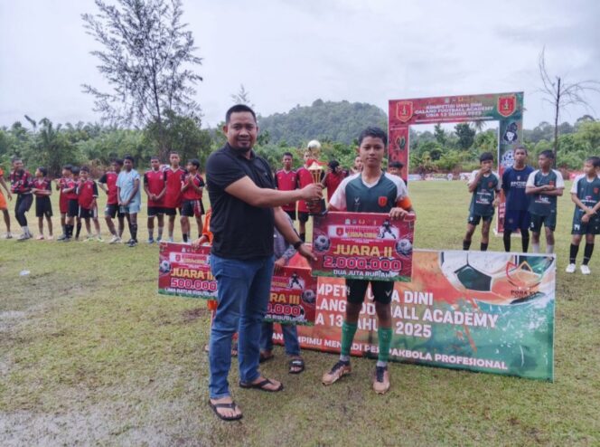 
 Masri, Pengurus PSSI Aceh Jaya sekaligus Ketua KNPI Aceh Jaya menyerahkan hadiah pembinaan untuk Runner-up turnamen sepak bola kaki usia 13 tahun ( U-13) tahun 2025 SSB CFA, Sabtu (12/7/2025) (Foto/Ist) 