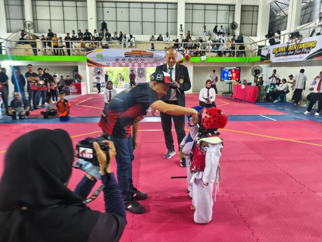 
 Bupati Aceh Jaya, Safwandi mengalungkan medali kepada atlet  pada Open Tournament Taekwondo Piala Bupati Aceh Jaya Tahun 2026 di Gelanggang Olahraga (GoR) PBVSI setempat, Sabtu (26/9/2026) (Foto/AJP-Putri)